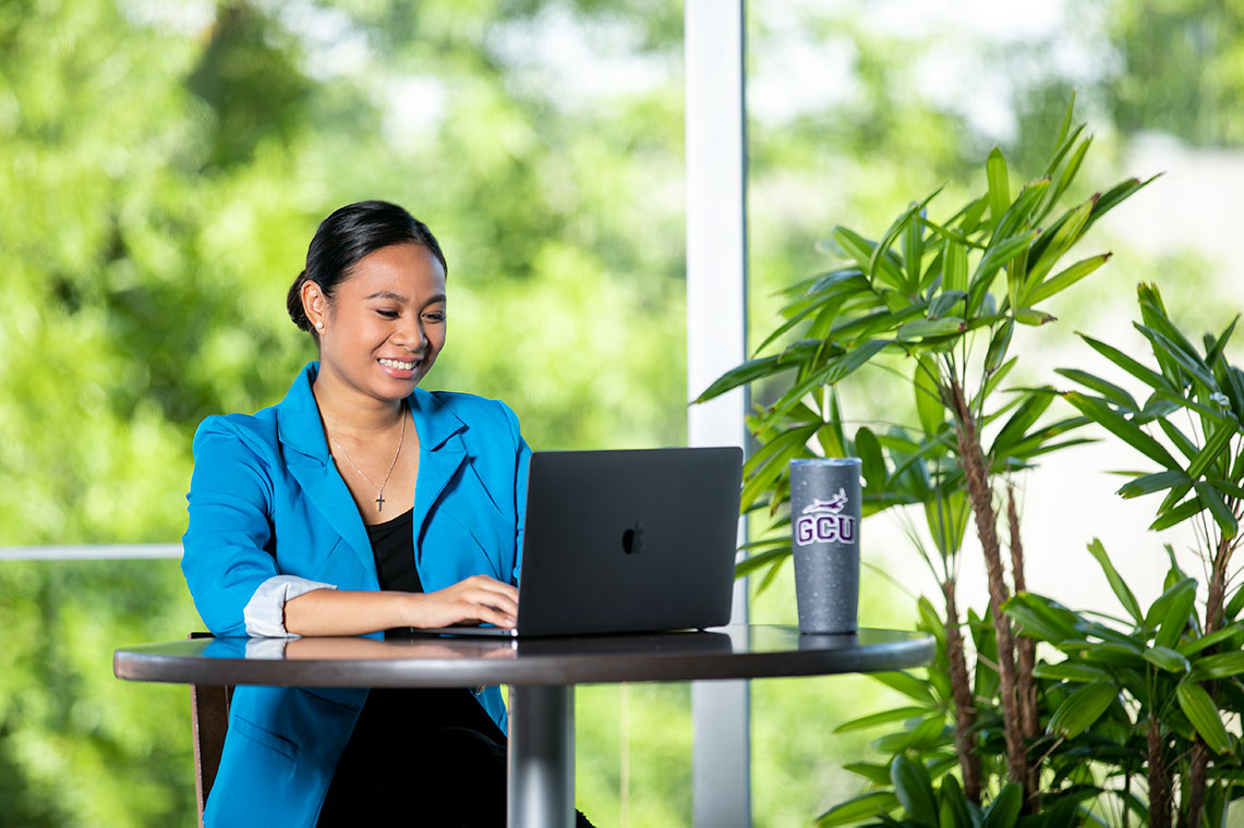 Smiling teacher at desk taking online professional development training